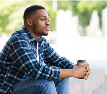 Adult man praying at an empty bed in the hospital ward.